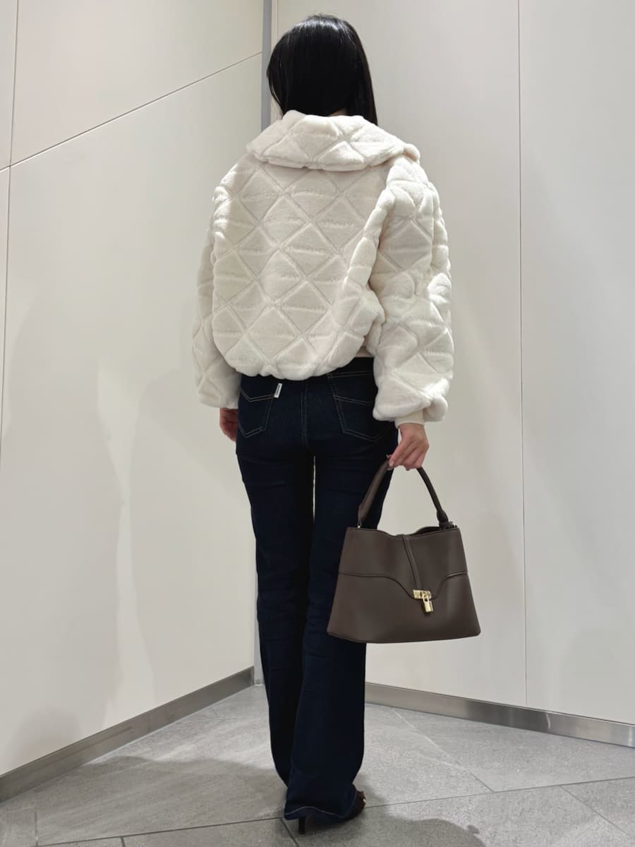 ブラウン系のハンドバッグ、ブルー系のデニムパンツ、ホワイト系のブルゾンを着用したレディースの秋コーディネートの3枚目の写真