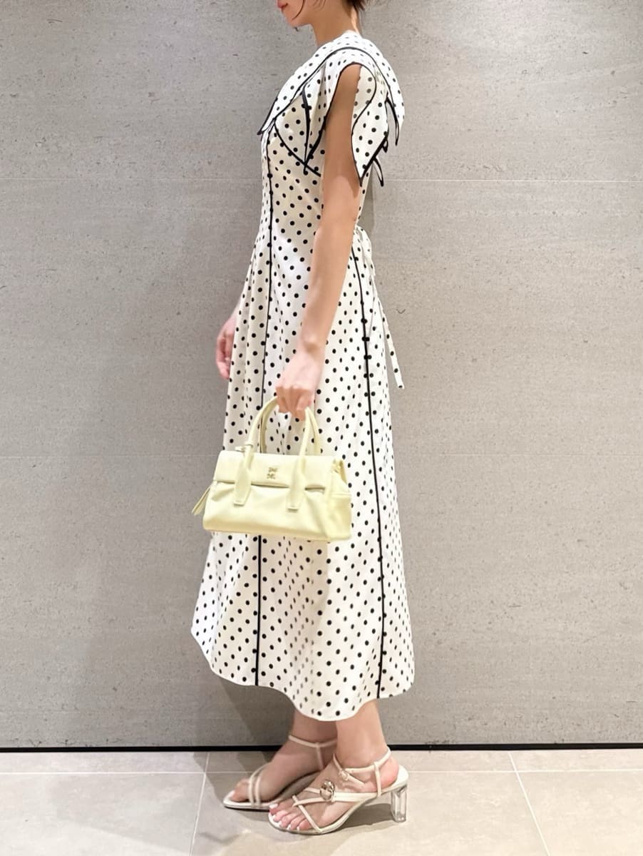 イエロー系のボストンバッグ、ホワイト系のワンピースを着用したレディースの春コーディネートの2枚目の写真
