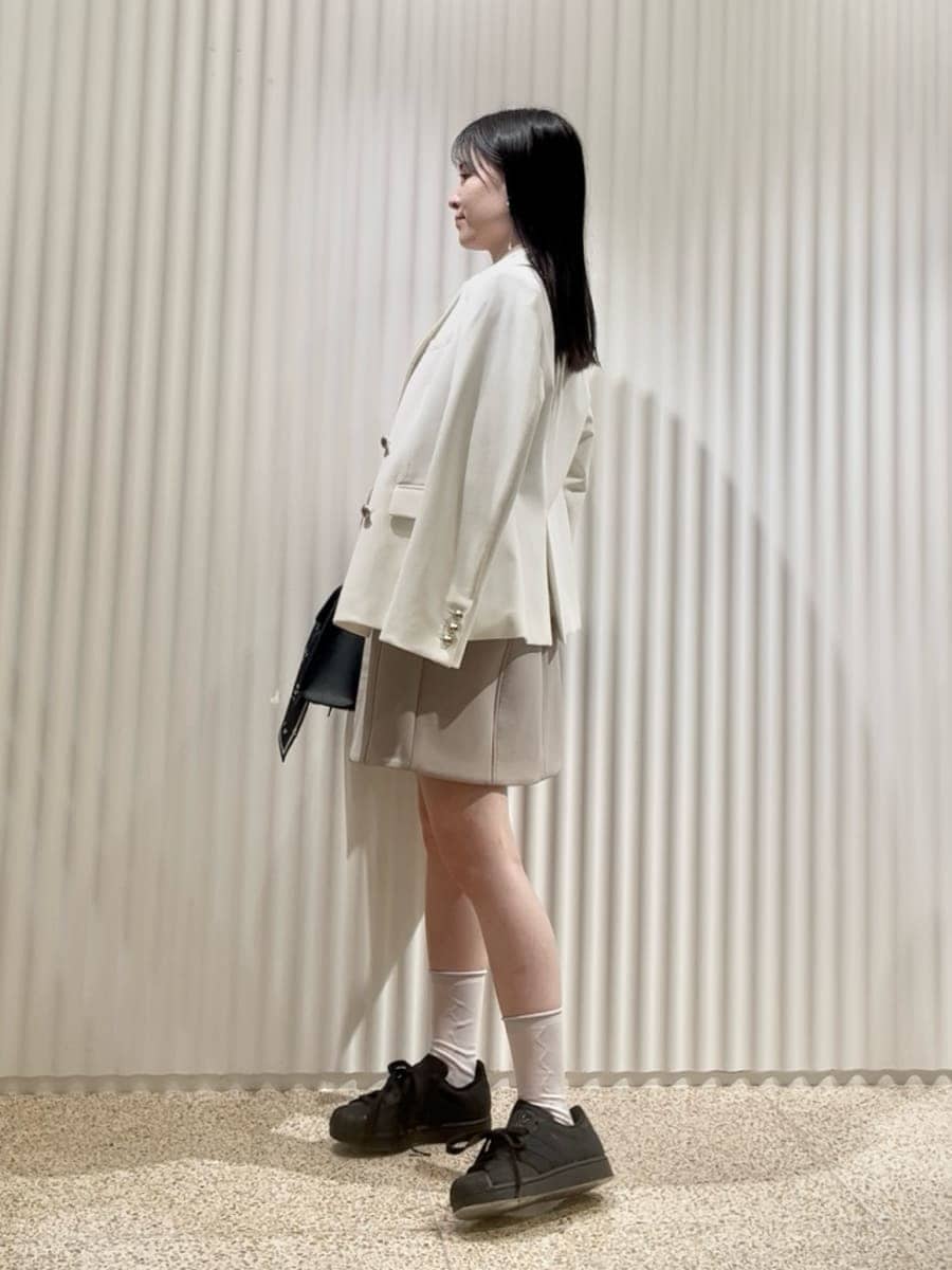 ホワイト系のテーラードジャケット、グリーン系のワンピース、ブラック系のハンドバッグを着用したレディースの冬コーディネートの2枚目の写真