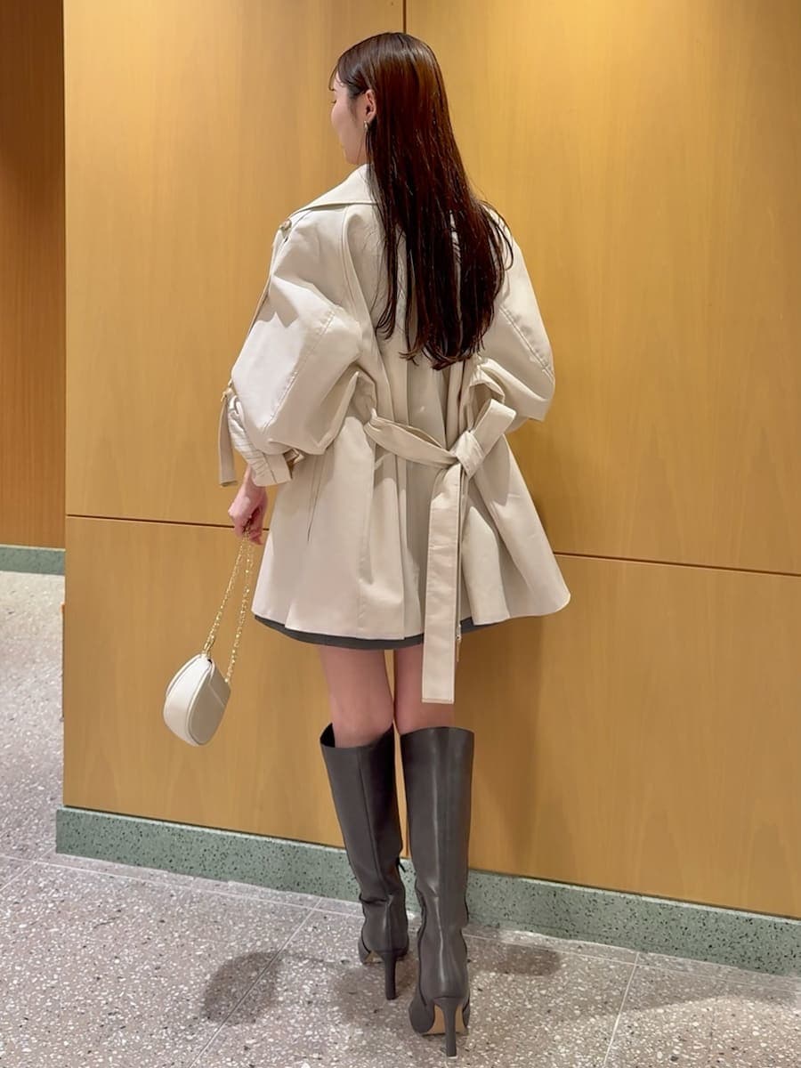 グレー系のブーツ、ホワイト系のトレンチコート、グレー系のワンピースを着用したレディースの冬コーディネートの4枚目の写真