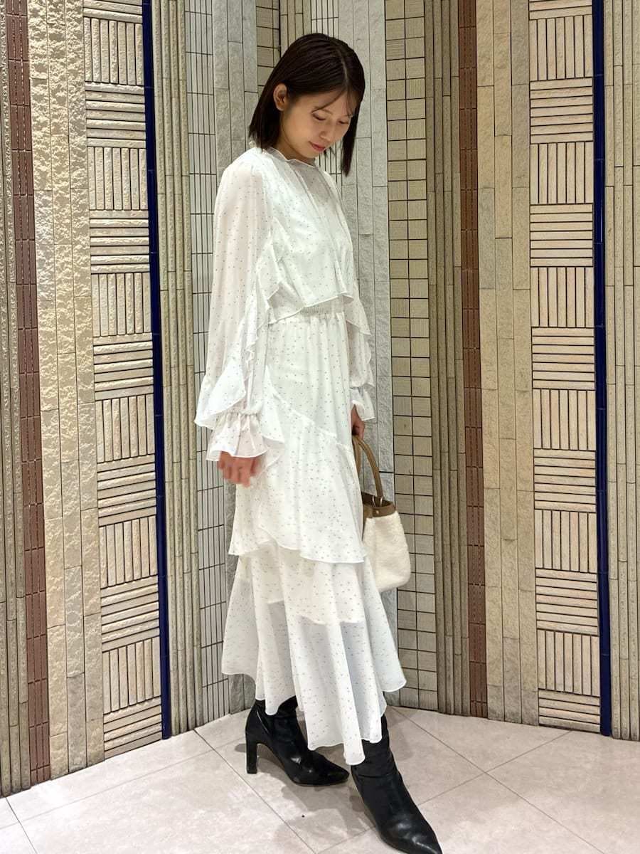 イエロー系のトートバッグ、ブラック系のブーツ、その他のワンピースを着用したレディースの冬コーディネートの2枚目の写真