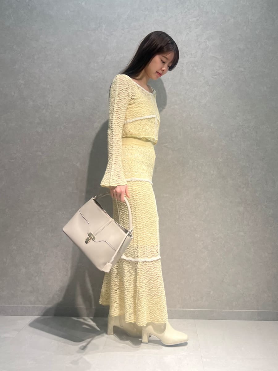 イエロー系のスカート、イエロー系のニット/セーター、ホワイト系のハンドバッグを着用したレディースの春コーディネートの2枚目の写真