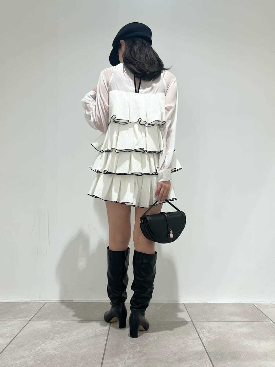 ブラック系のハンドバッグ、ホワイト系のドレス、ブラック系のブーツを着用したレディースの冬コーディネートの3枚目の写真