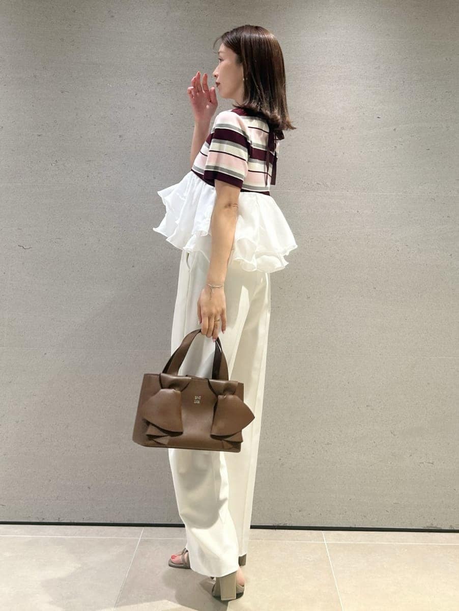 ホワイト系のスラックス、ピンク系のTシャツ/カットソー、ブラウン系のハンドバッグを着用したレディースの春コーディネートの3枚目の写真