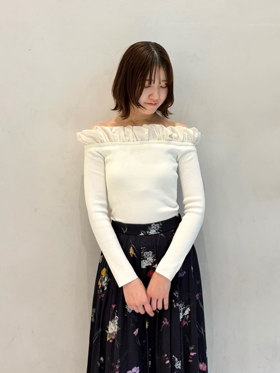 ブラック系のショルダーバッグ、ブルー系のスカート、ホワイト系のニット/セーターを着用したレディースの冬コーディネートの2枚目の写真