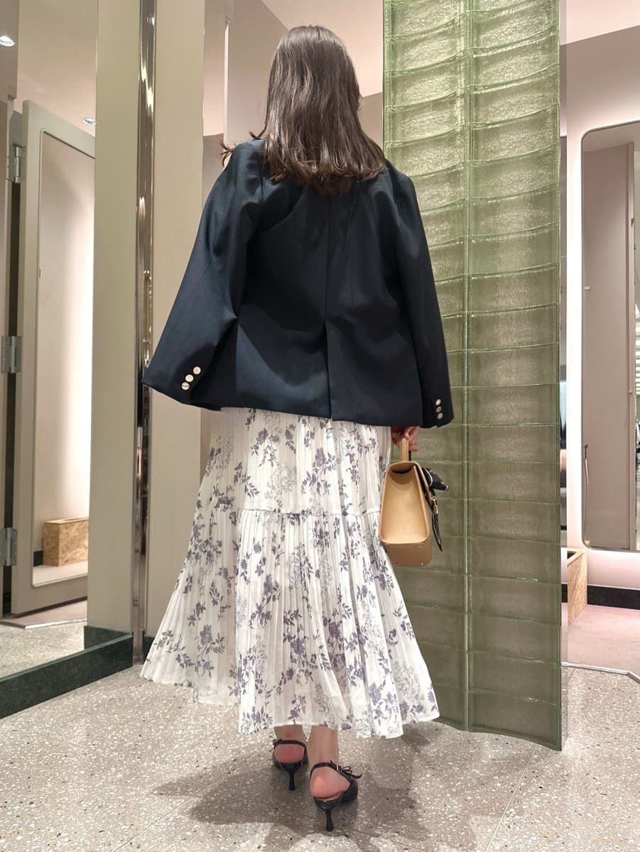 ブルー系のテーラードジャケット、ホワイト系のワンピース、イエロー系のハンドバッグを着用したレディースの秋コーディネートの4枚目の写真