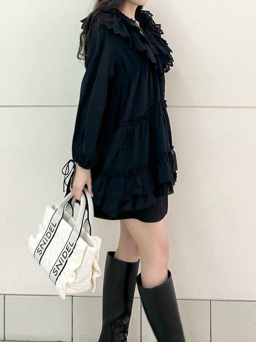 ブラック系のブーツ、ホワイト系のハンドバッグ、ブラック系のスカートを着用したレディースの冬コーディネートの6枚目の写真