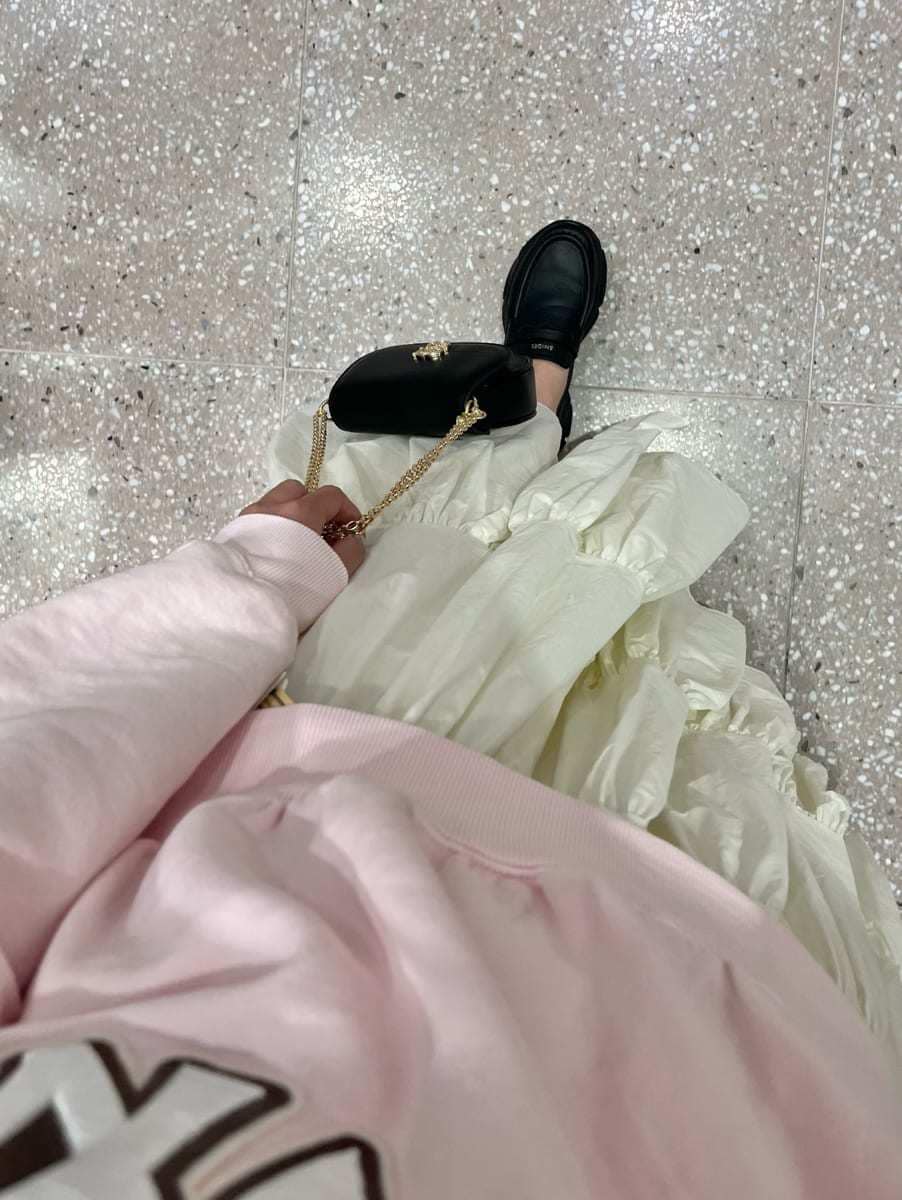 ホワイト系のスカート、ピンク系のスウェット、ブラック系のショルダーバッグを着用したレディースの春コーディネートの6枚目の写真
