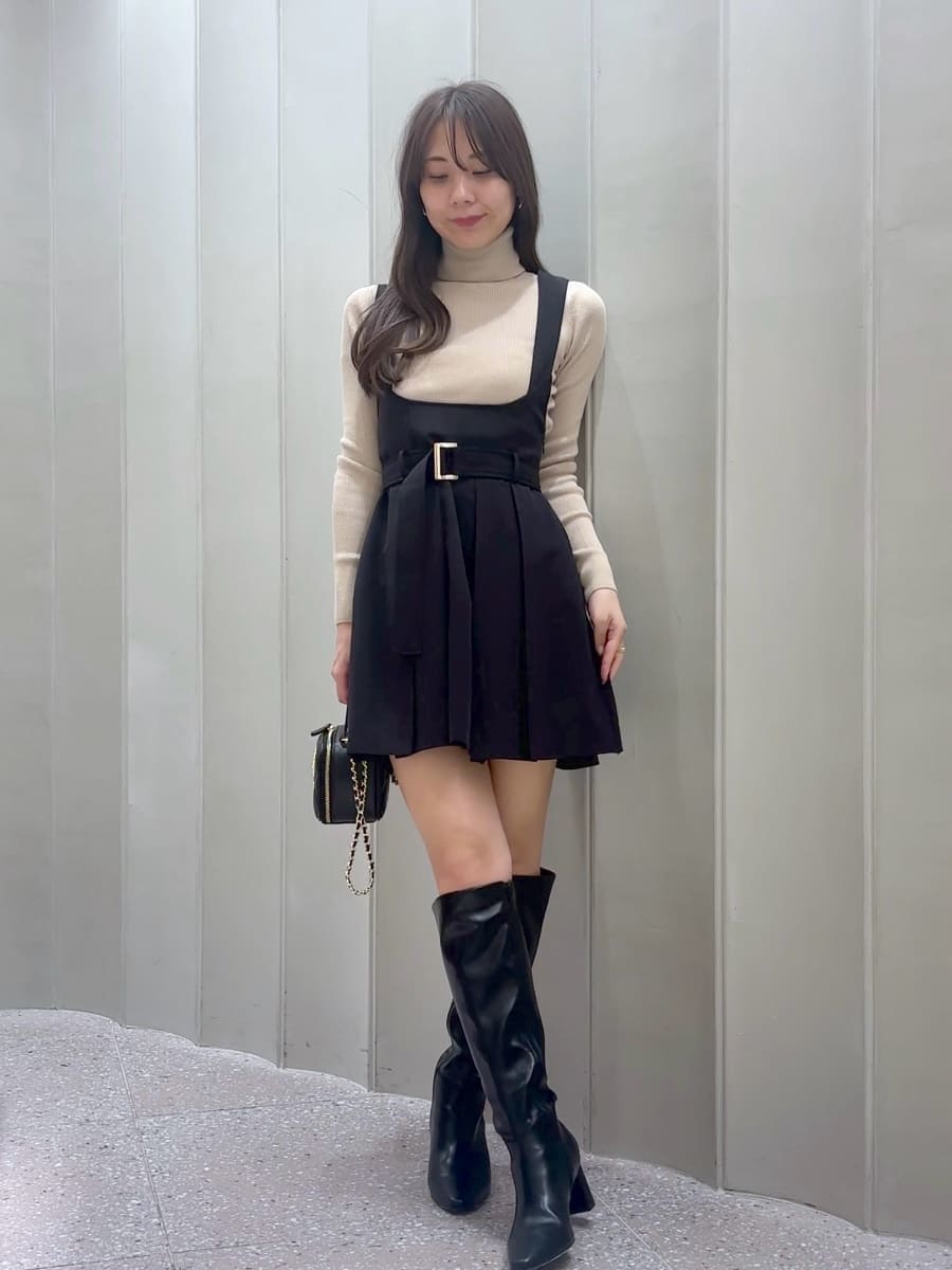 ブラック系のワンピース、ベージュ系のニット/セーター、ブラック系のブーツを着用したレディースの秋コーディネートの2枚目の写真