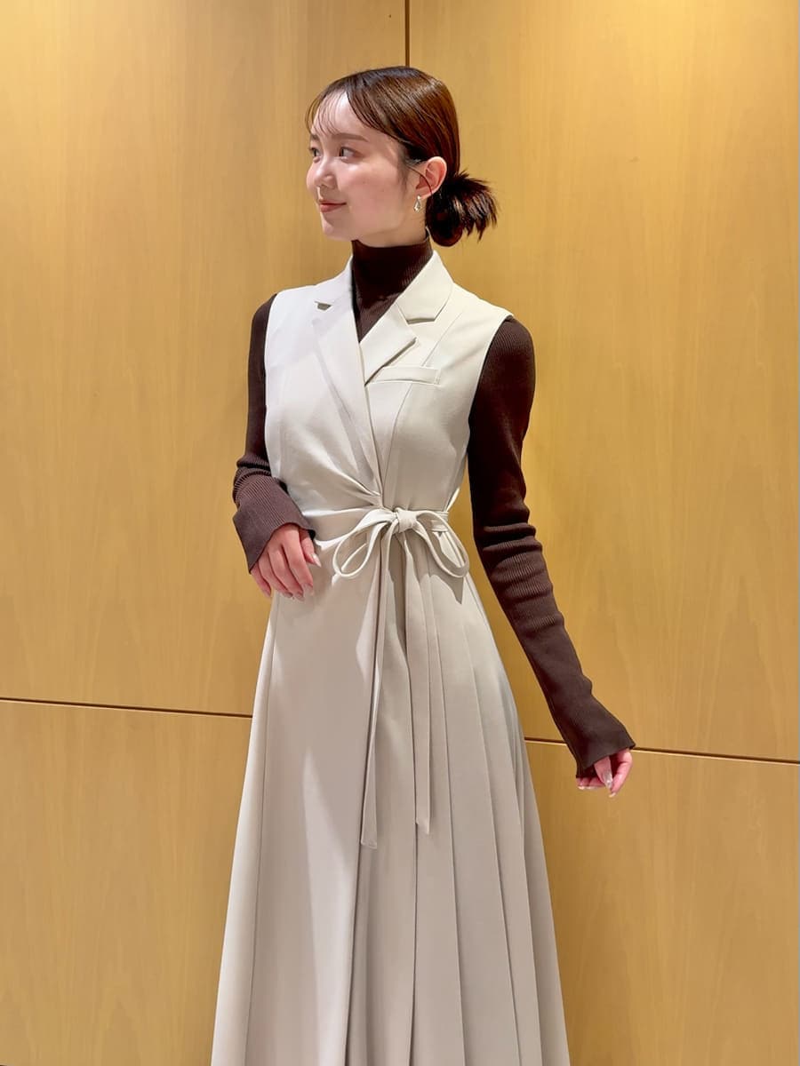 ピンク系のステンカラーコート、ベージュ系のワンピース、ブラウン系のニット/セーターを着用したレディースの秋コーディネートの7枚目の写真