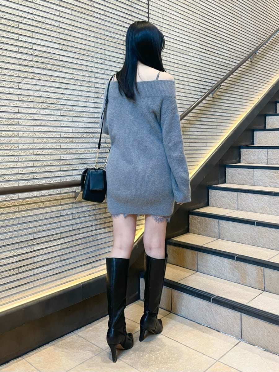 グレー系のワンピース、ブラック系のブーツ、ホワイト系のチェスターコートを着用したレディースの冬コーディネートの5枚目の写真