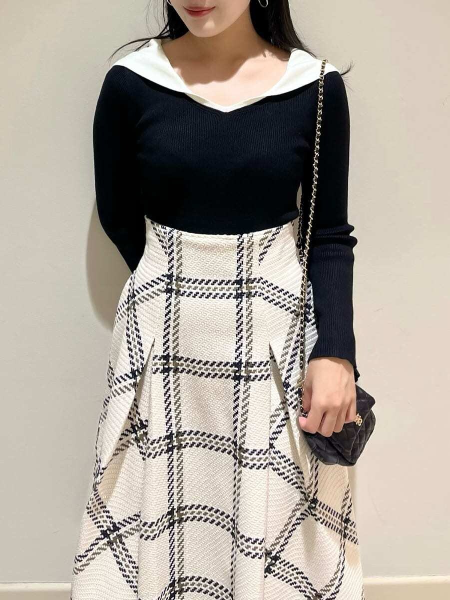 ブラック系のニット/セーター、ホワイト系のスカート、ブラック系のショルダーバッグを着用したレディースの秋コーディネートの3枚目の写真