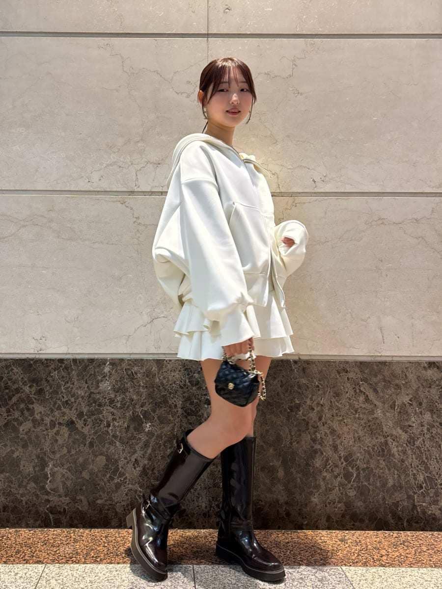 ブラウン系のブーツ、ブラック系のショルダーバッグ、ホワイト系のパーカーを着用したレディースの冬コーディネートの4枚目の写真