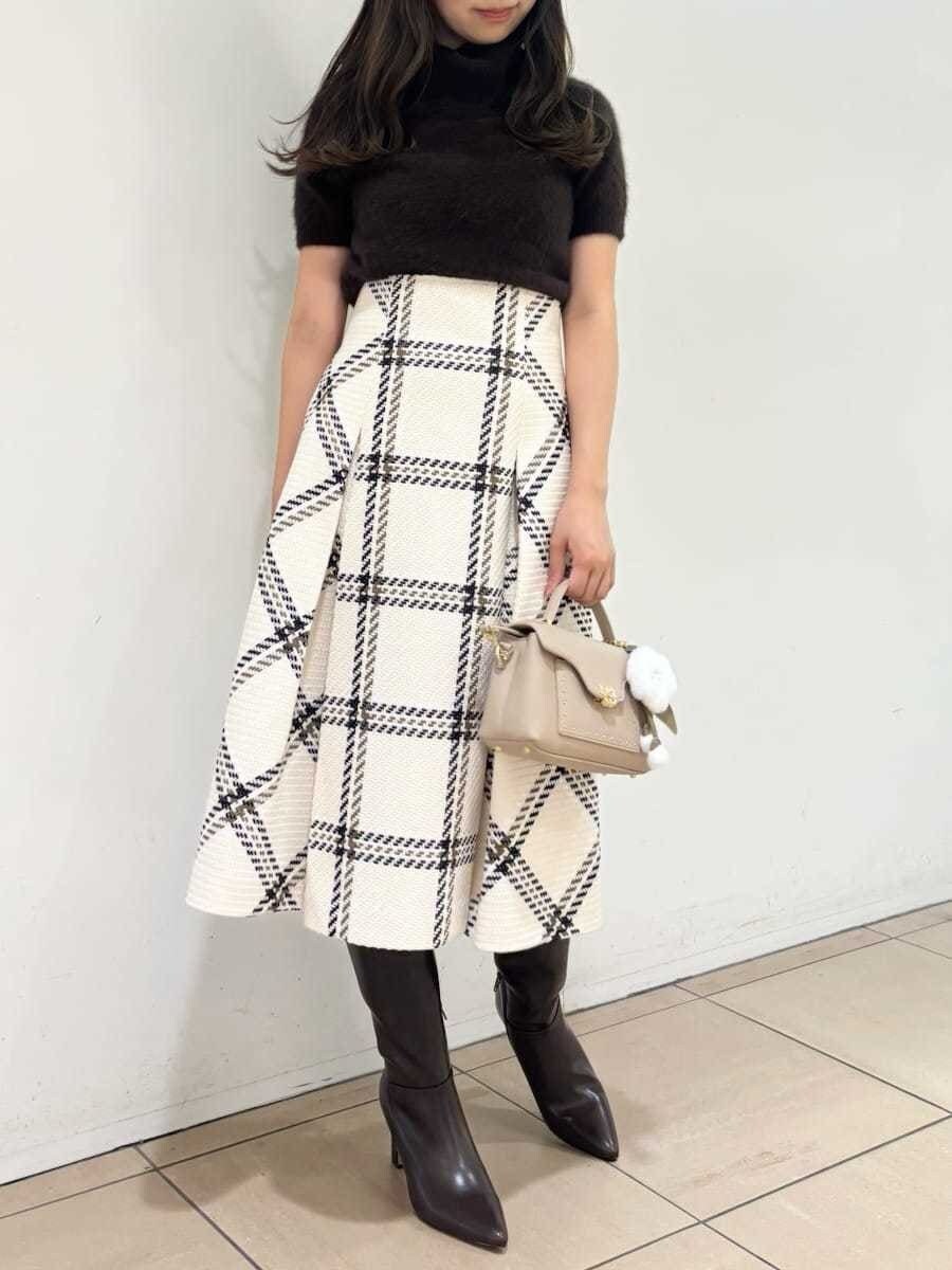 ブラウン系のニット/セーター、ホワイト系のスカート、ブラウン系のブーツを着用したレディースの秋コーディネートの2枚目の写真