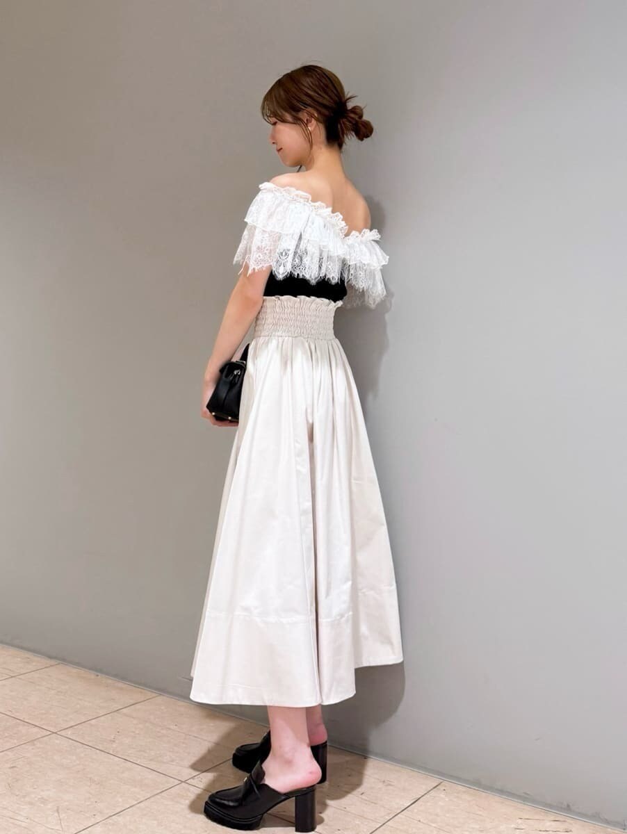 ブラック系のニット/セーター、ホワイト系のスカート、ブラック系のショルダーバッグを着用したレディースの夏コーディネートの2枚目の写真
