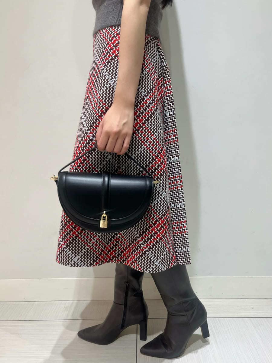 グレー系のニット/セーター、レッド系のスカート、ブラック系のハンドバッグを着用したレディースの秋コーディネートの6枚目の写真
