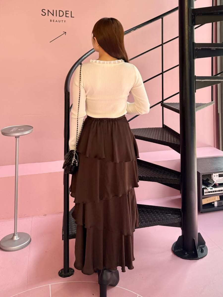 ホワイト系のニット/セーター、ブラウン系のスカート、ブラック系のブーツを着用したレディースの秋コーディネートの3枚目の写真