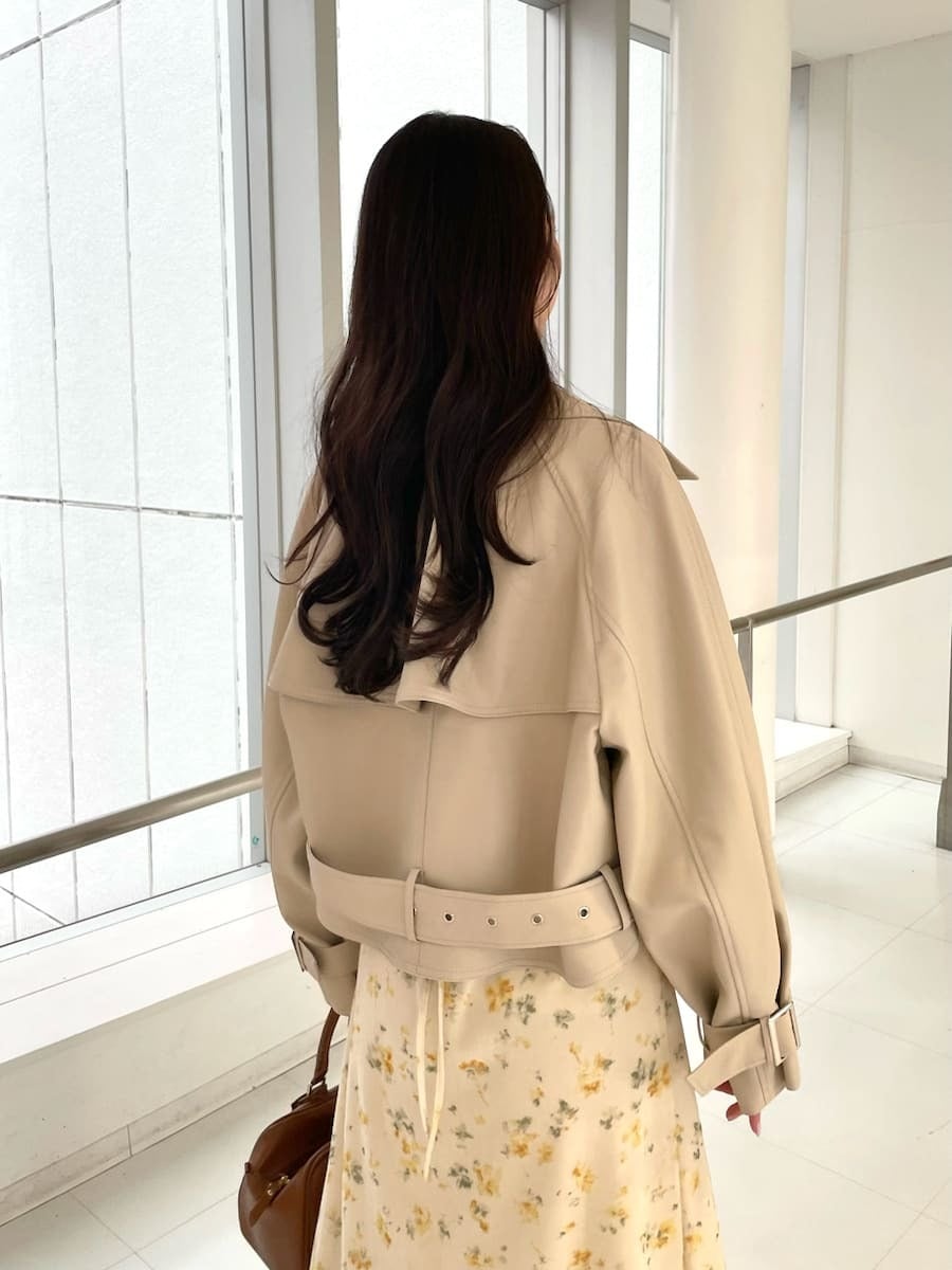 イエロー系のワンピース、ベージュ系のトレンチコート、イエロー系のボストンバッグを着用したレディースの冬コーディネートの3枚目の写真