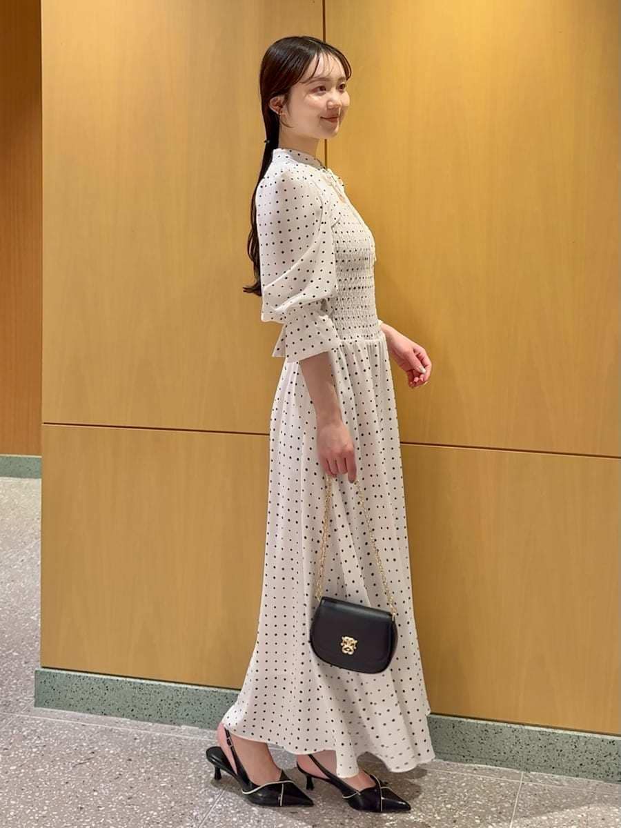 ブラック系のパンプス、ブラック系のショルダーバッグ、ホワイト系のワンピースを着用したレディースの春コーディネートの2枚目の写真