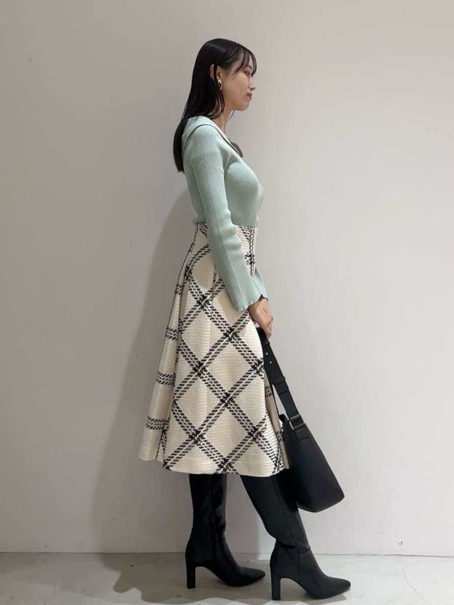 グリーン系のニット/セーター、ホワイト系のスカート、ブラック系のブーツを着用したレディースの秋コーディネートの4枚目の写真