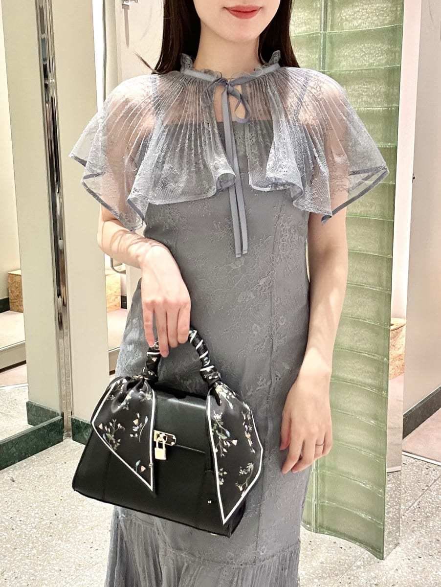 グレー系のドレス、ブラック系のパンプス、ブラック系のハンドバッグを着用したレディースの冬コーディネートの2枚目の写真