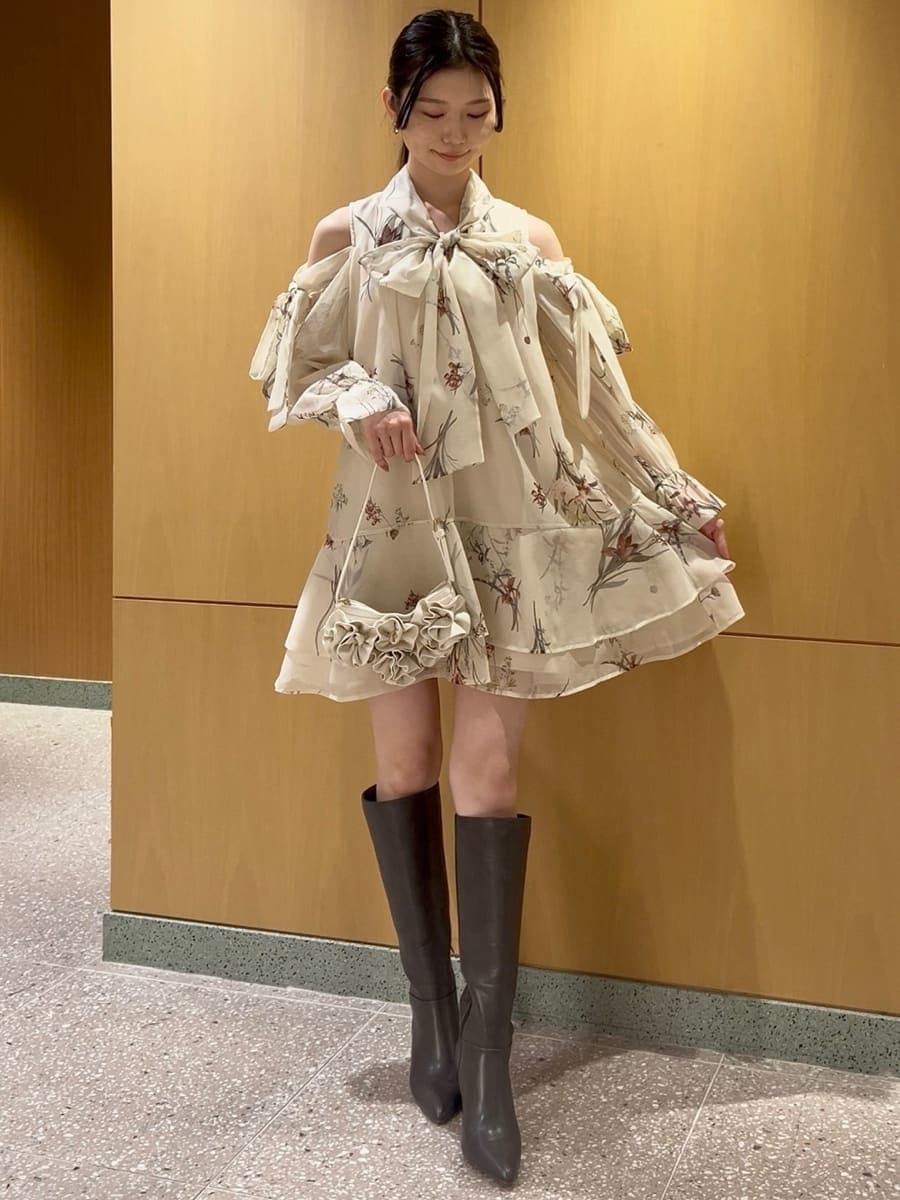 グレー系のブーツ、イエロー系のワンピース、ホワイト系のハンドバッグを着用したレディースの冬コーディネートの2枚目の写真