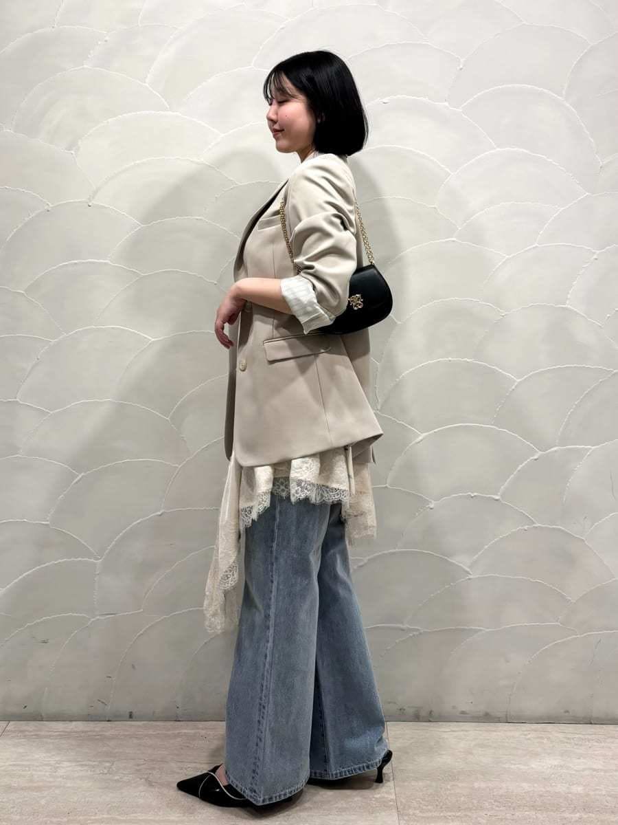 ベージュ系のテーラードジャケット、ブルー系のデニムパンツ、ホワイト系のキャミソールを着用したレディースの春コーディネートの2枚目の写真