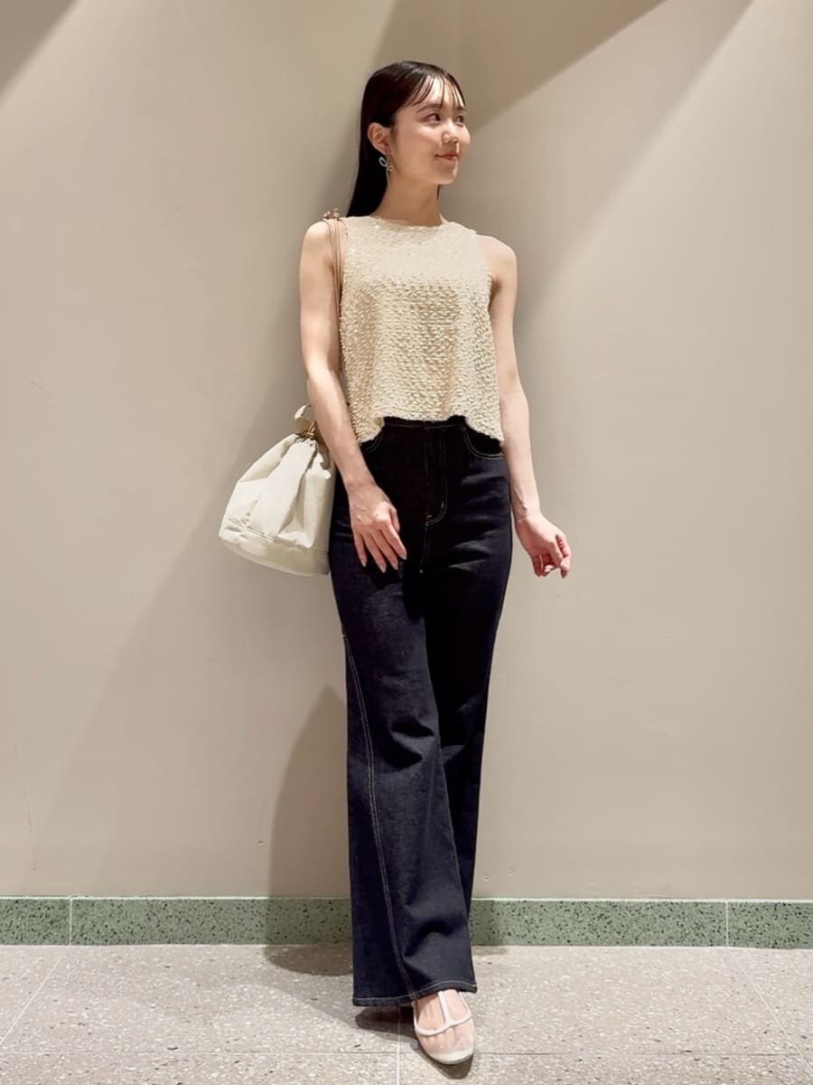ホワイト系のタンクトップ、ブルー系のデニムパンツ、ベージュ系のハンドバッグを着用したレディースの夏コーディネートの2枚目の写真