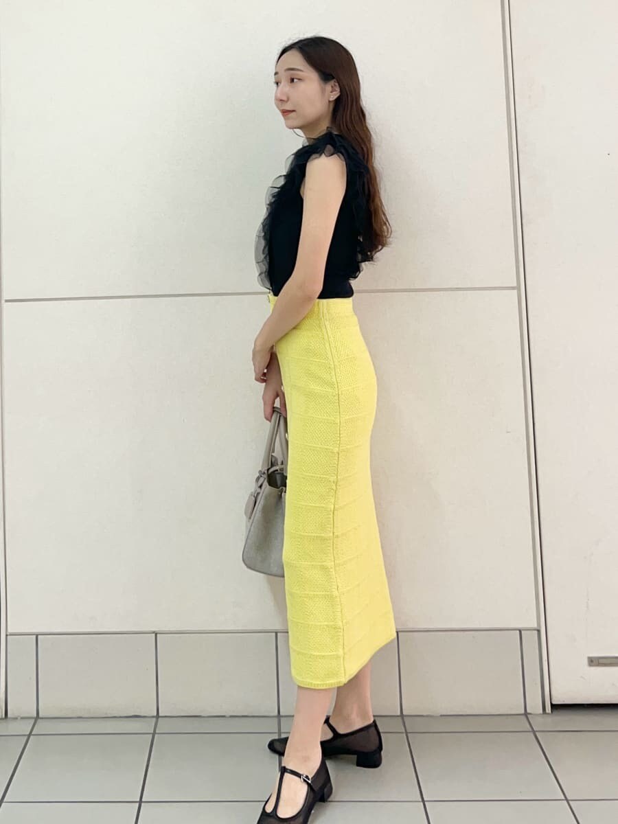 ブラック系のニット/セーター、イエロー系のスカート、ピンク系のハンドバッグを着用したレディースの夏コーディネートの3枚目の写真