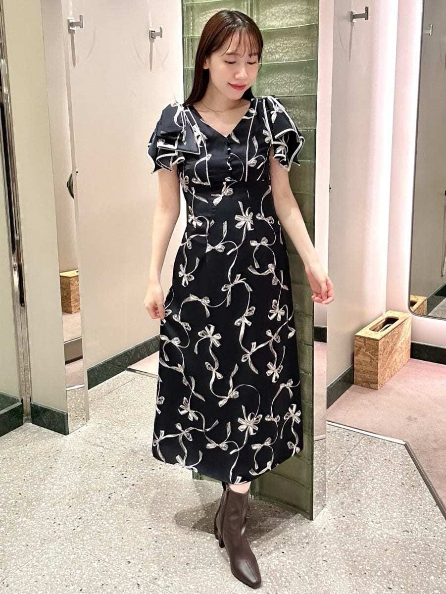 ブラウン系のチェスターコート、ブルー系のワンピース、レッド系のブーツを着用したレディースの秋コーディネートの3枚目の写真