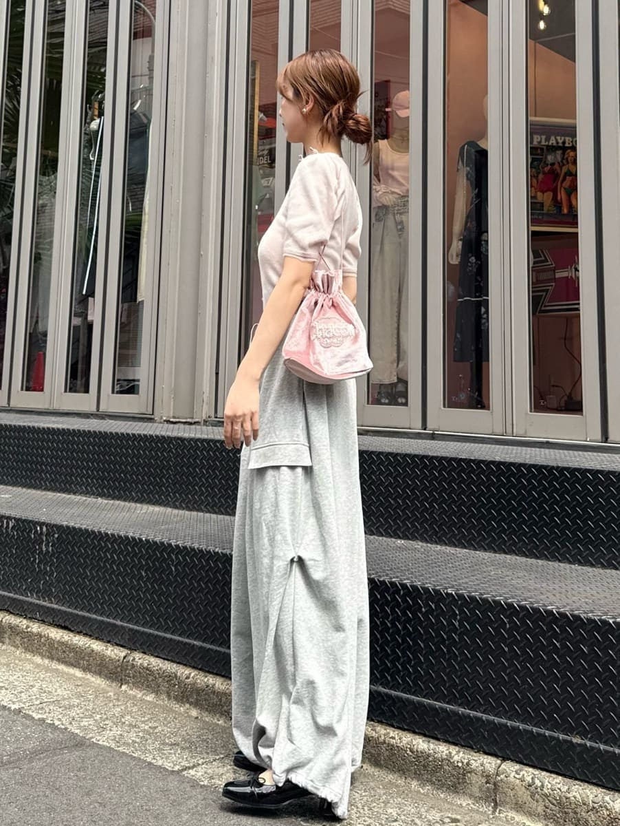 ピンク系のニット/セーター、グレー系のその他パンツ、ピンク系のハンドバッグを着用したレディースの夏コーディネートの2枚目の写真