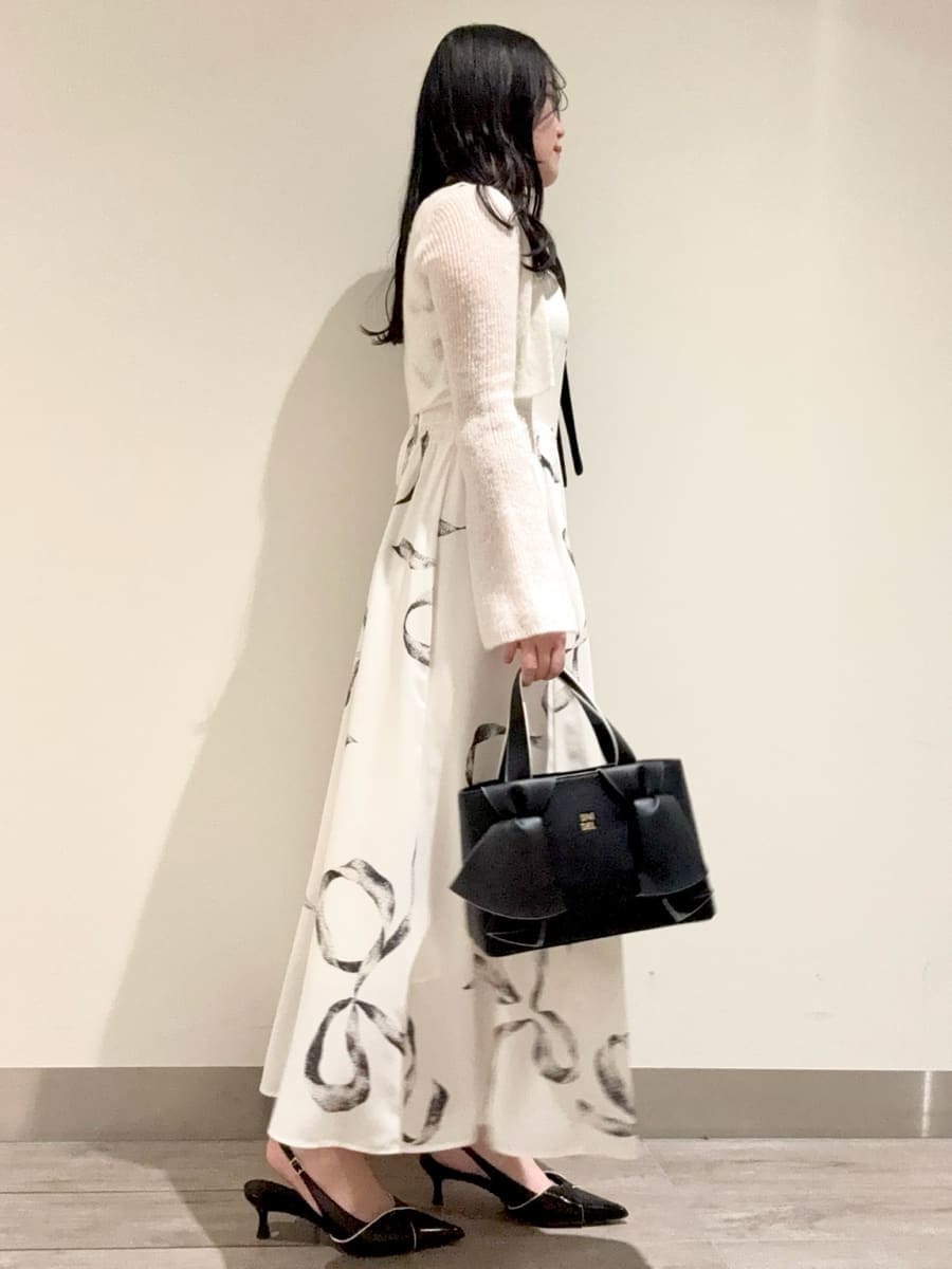 ホワイト系のワンピース、ブラック系のパンプス、ブラック系のハンドバッグを着用したレディースの冬コーディネートの3枚目の写真