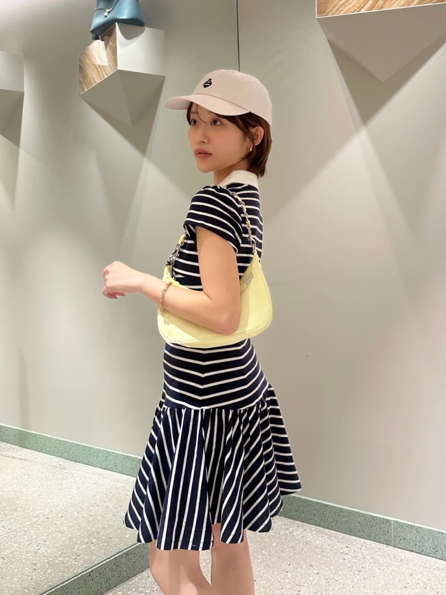 ブルー系のワンピース、イエロー系のショルダーバッグ、ホワイト系のキャップを着用したレディースの夏コーディネートの4枚目の写真