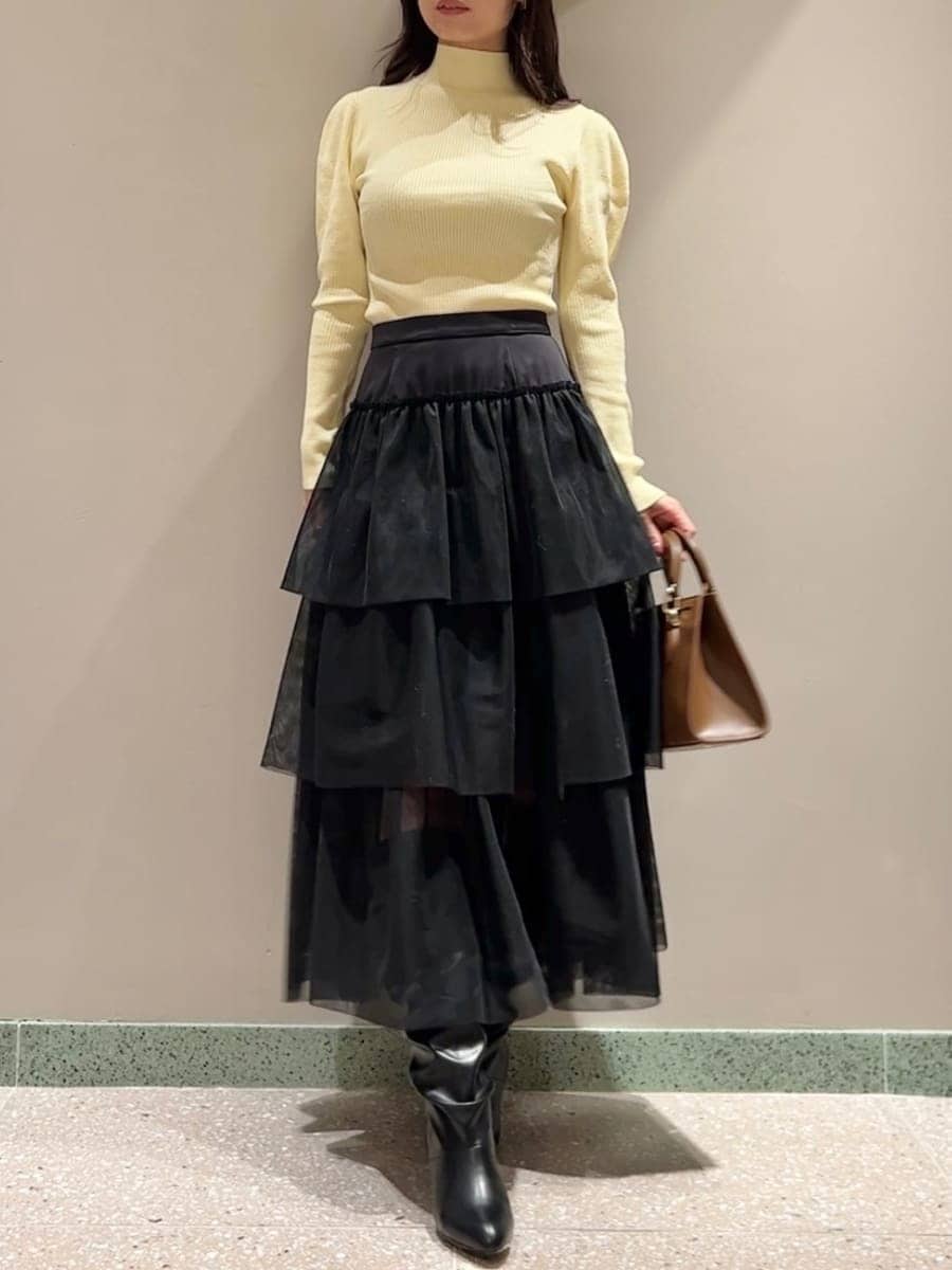 イエロー系のニット/セーター、ホワイト系のムートンコート、ブラック系のスカートを着用したレディースの秋コーディネートの5枚目の写真