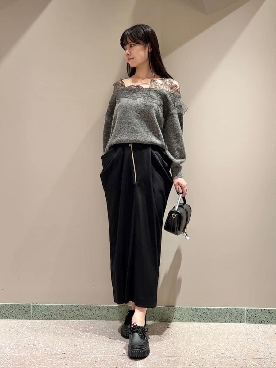 グレー系のニット/セーター、ブラック系のスカート、ブラック系のハンドバッグを着用したレディースの秋コーディネートの3枚目の写真