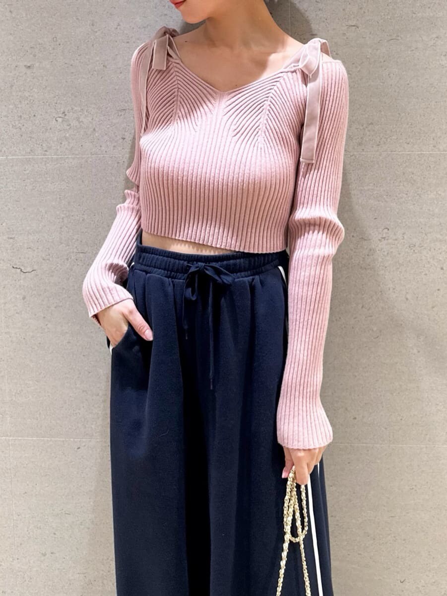 ピンク系のニット/セーター、ホワイト系のショルダーバッグ、レッド系のイヤリングを着用したレディースの夏コーディネートの3枚目の写真