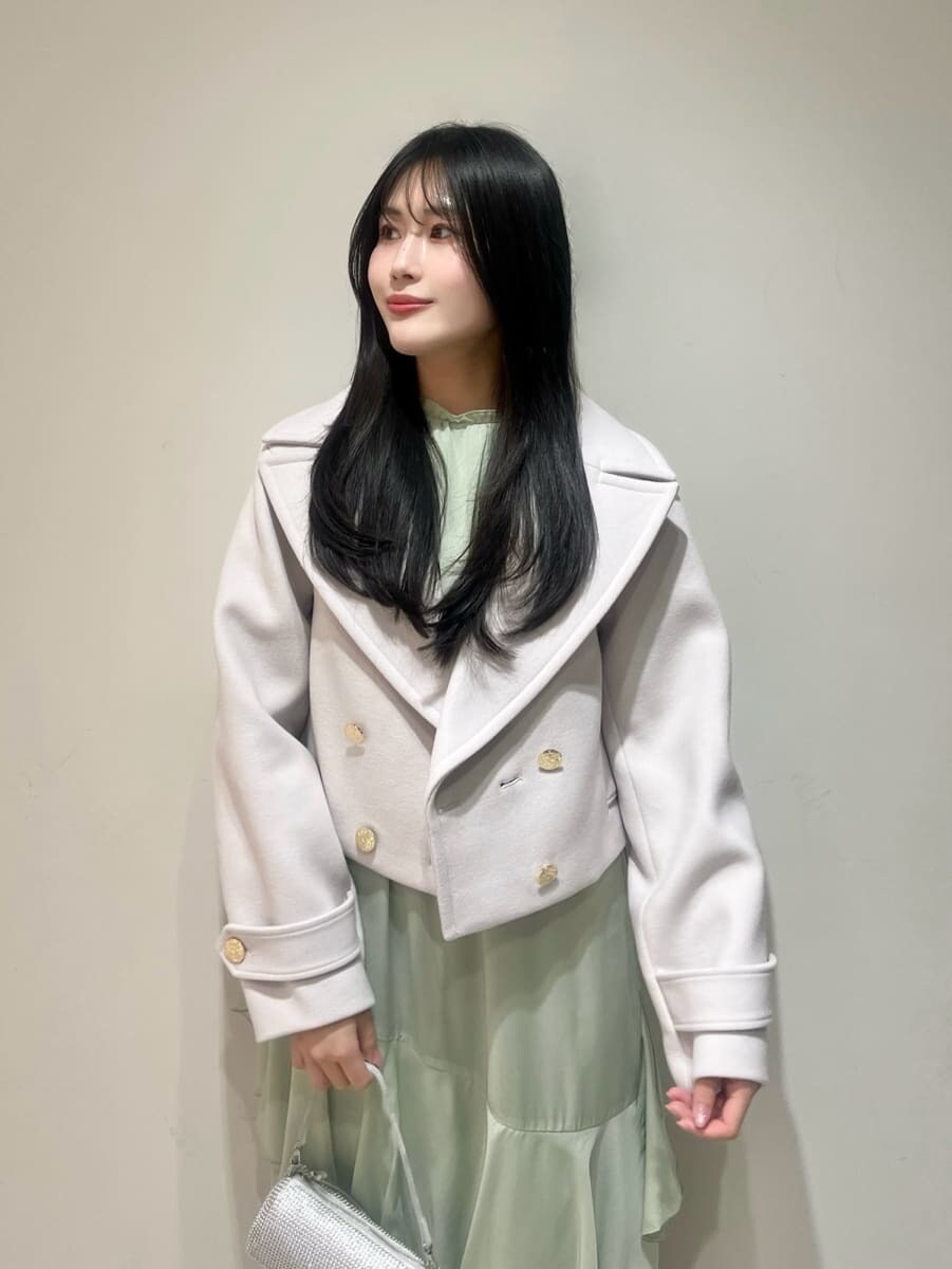 ブラック系のブーツ、ベージュ系のピーコート、グリーン系のワンピースを着用したレディースの冬コーディネートの3枚目の写真