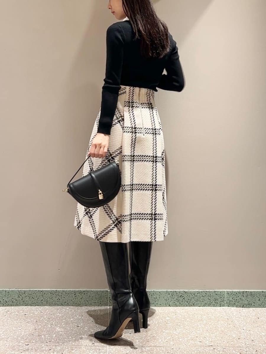 ブラック系のニット/セーター、ホワイト系のスカート、ブラック系のハンドバッグを着用したレディースの秋コーディネートの2枚目の写真