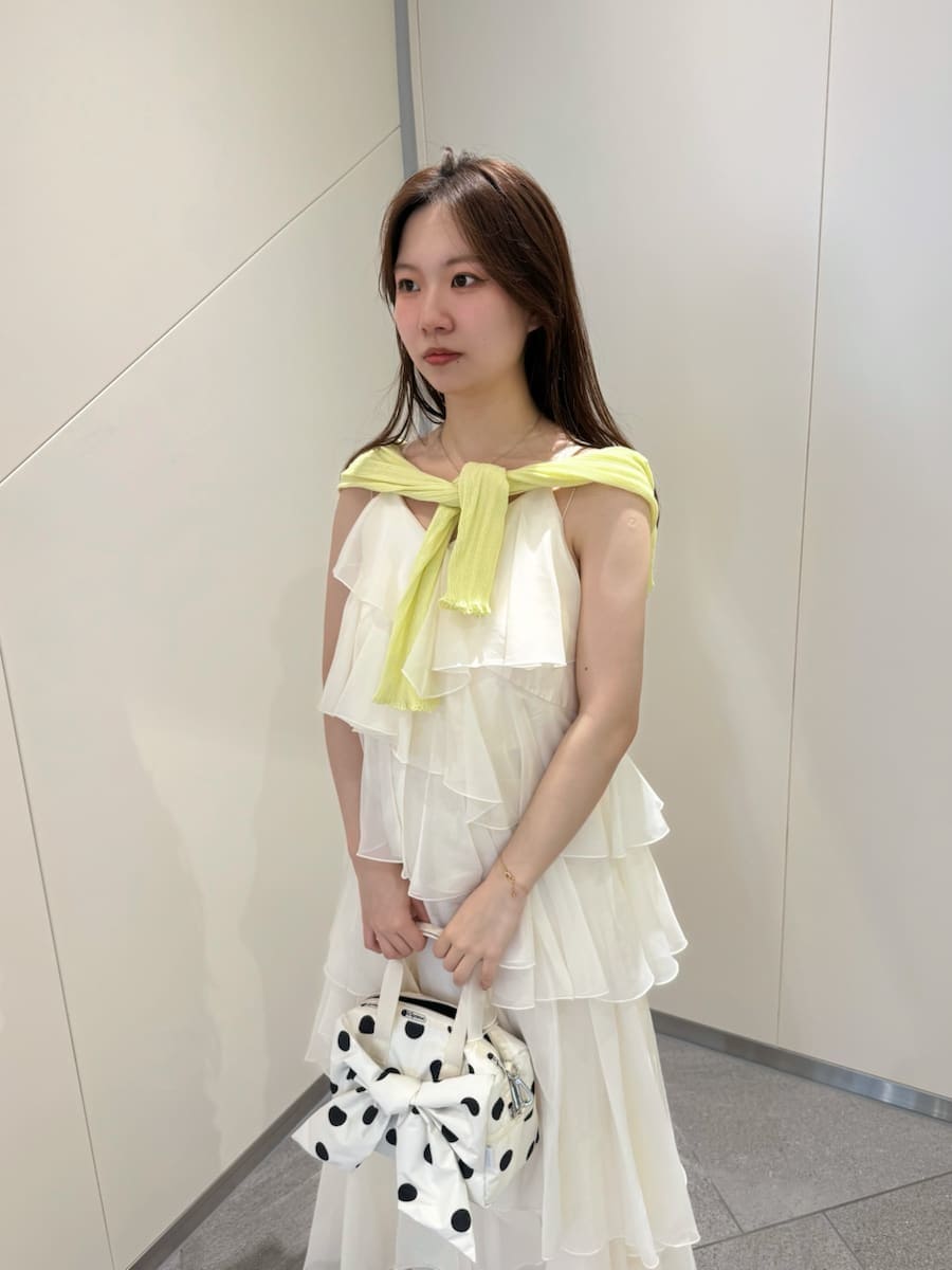 イエロー系のカーディガン/ボレロ、ホワイト系のショルダーバッグ、ホワイト系のドレスを着用したレディースの夏コーディネートの6枚目の写真