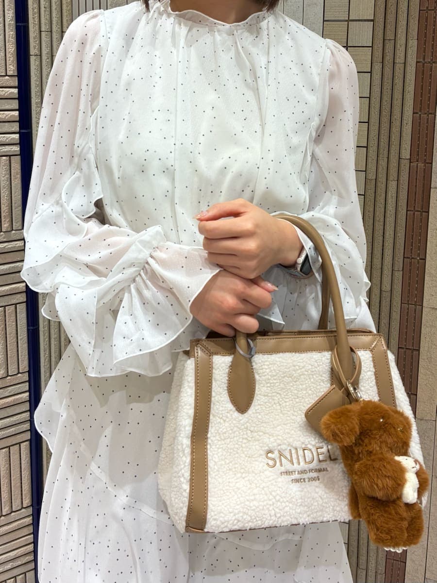 イエロー系のトートバッグ、ブラック系のブーツ、その他のワンピースを着用したレディースの冬コーディネートの6枚目の写真