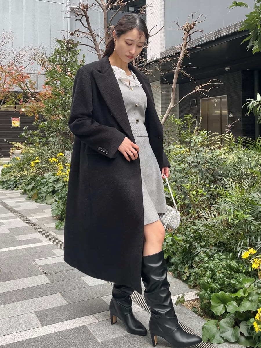 ブラック系のチェスターコート、グレー系のワンピースを着用したレディースの冬コーディネートの3枚目の写真
