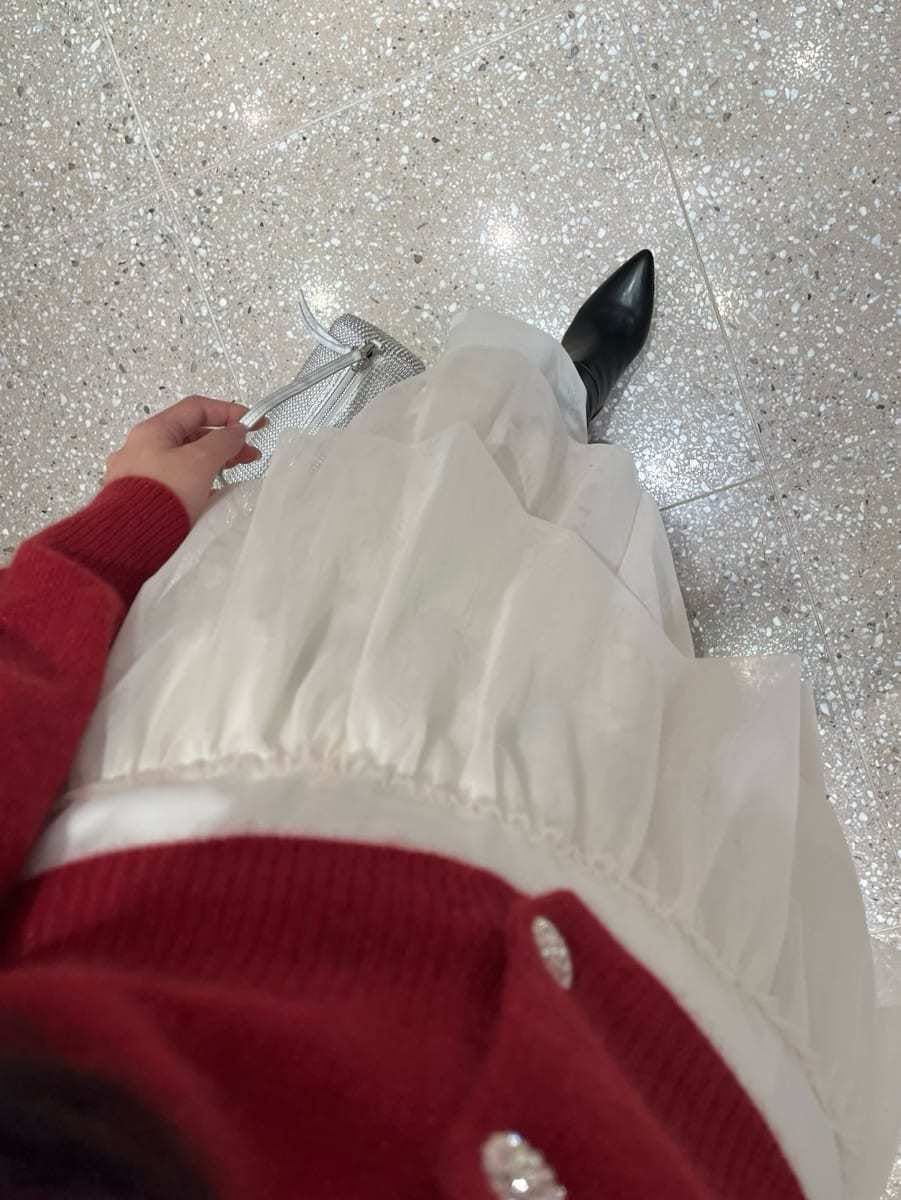 ブラック系のブーツ、ホワイト系のスカート、レッド系のカーディガン/ボレロを着用したレディースの冬コーディネートの8枚目の写真