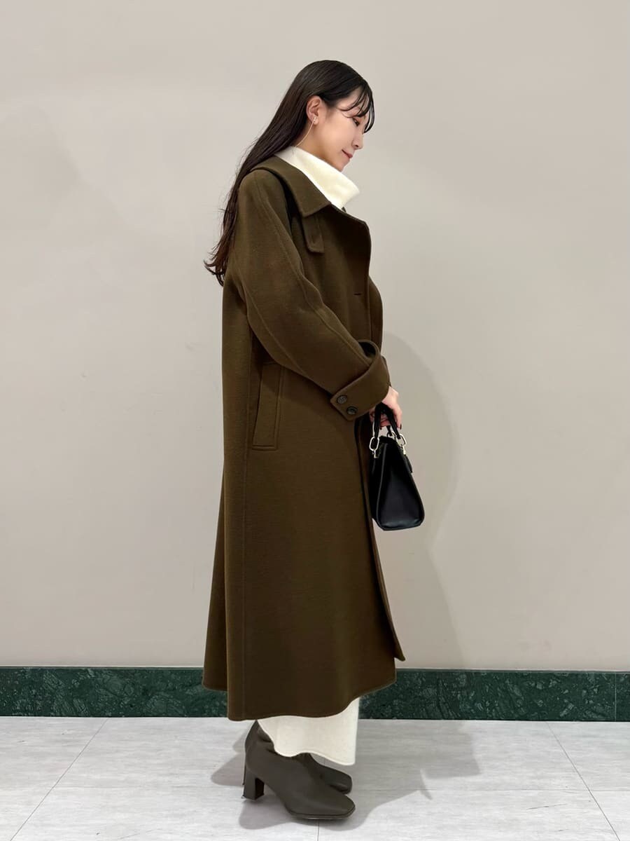 ホワイト系のワンピース、ブラック系のハンドバッグ、ブラウン系のチェスターコートを着用したレディースの冬コーディネートの3枚目の写真