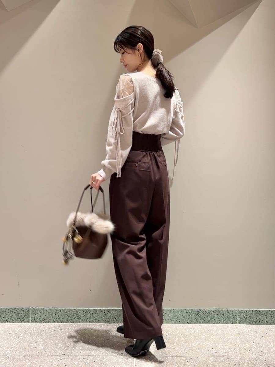 ブラウン系のスラックス、ピンク系のニット/セーター、ブラウン系のハンドバッグを着用したレディースの冬コーディネートの2枚目の写真