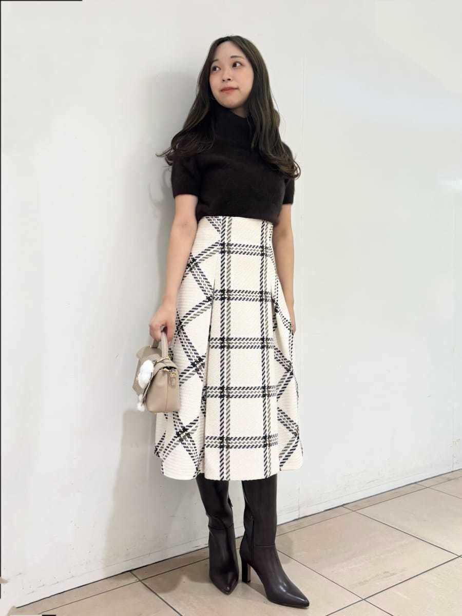 ブラウン系のニット/セーター、ホワイト系のスカート、ブラウン系のブーツを着用したレディースの秋コーディネートの3枚目の写真