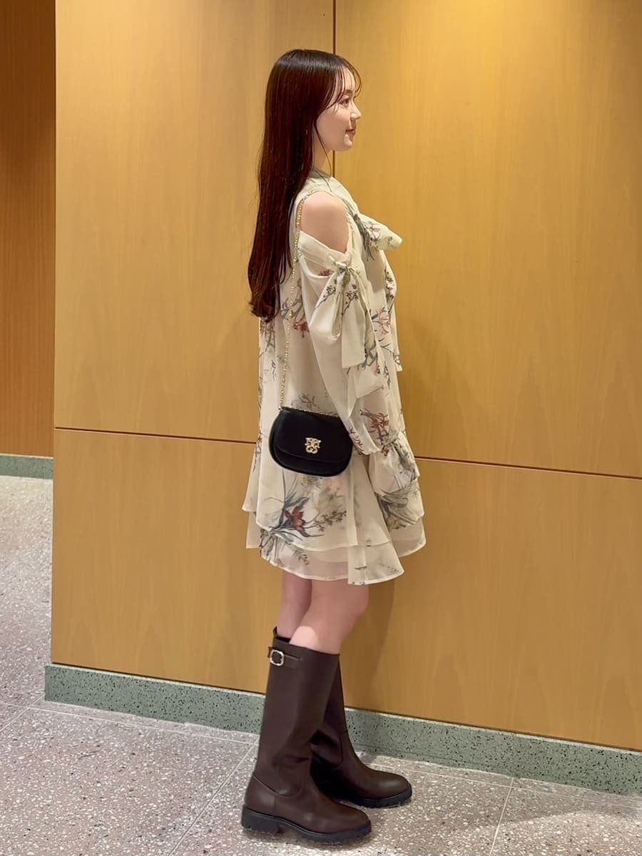 イエロー系のワンピース、ブラック系のショルダーバッグ、シルバー系のピアス（両耳用）を着用したレディースの冬コーディネートの3枚目の写真