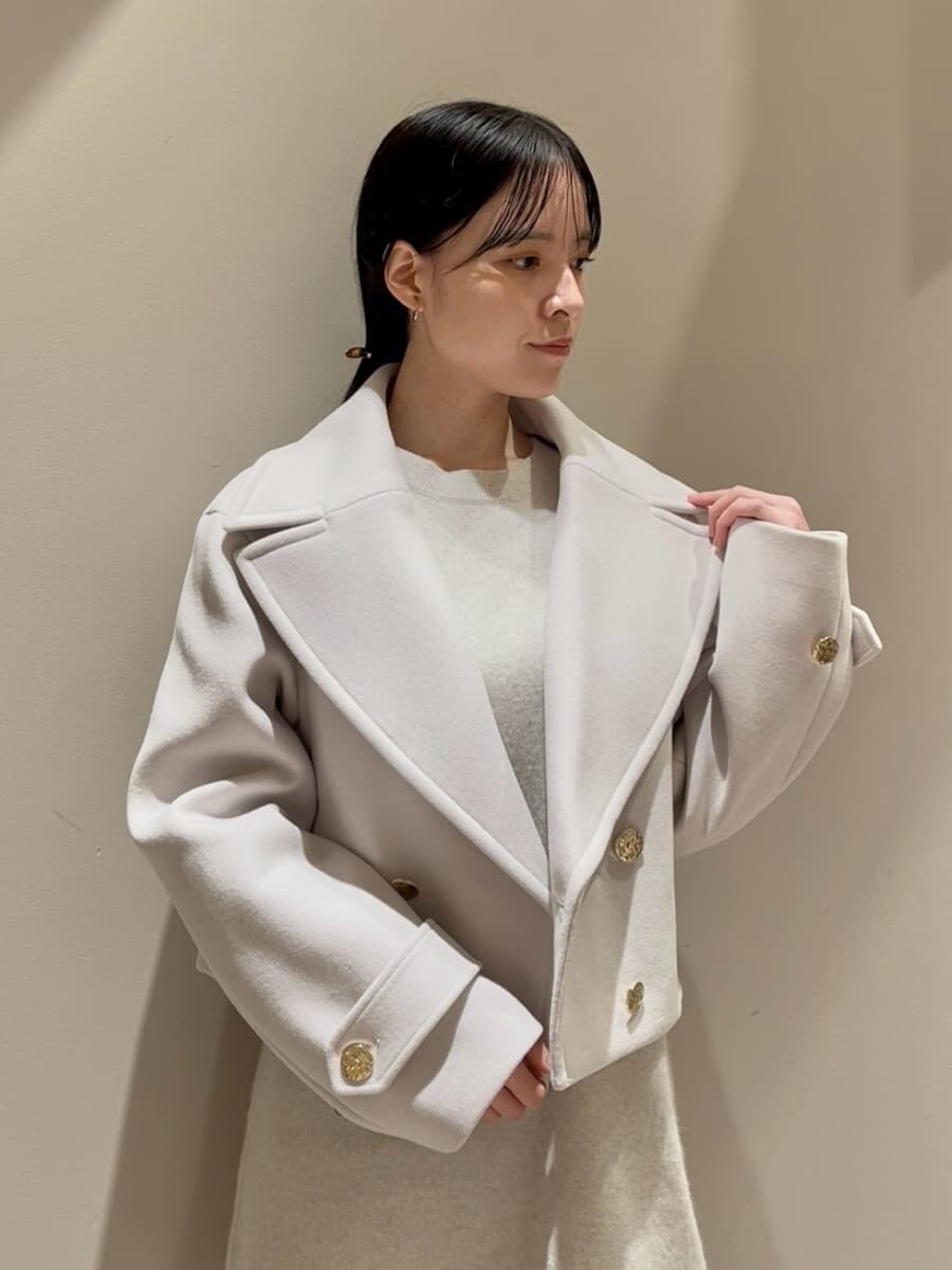 ホワイト系のワンピース、ベージュ系のピーコート、ブラック系のハンドバッグを着用したレディースの冬コーディネートの5枚目の写真