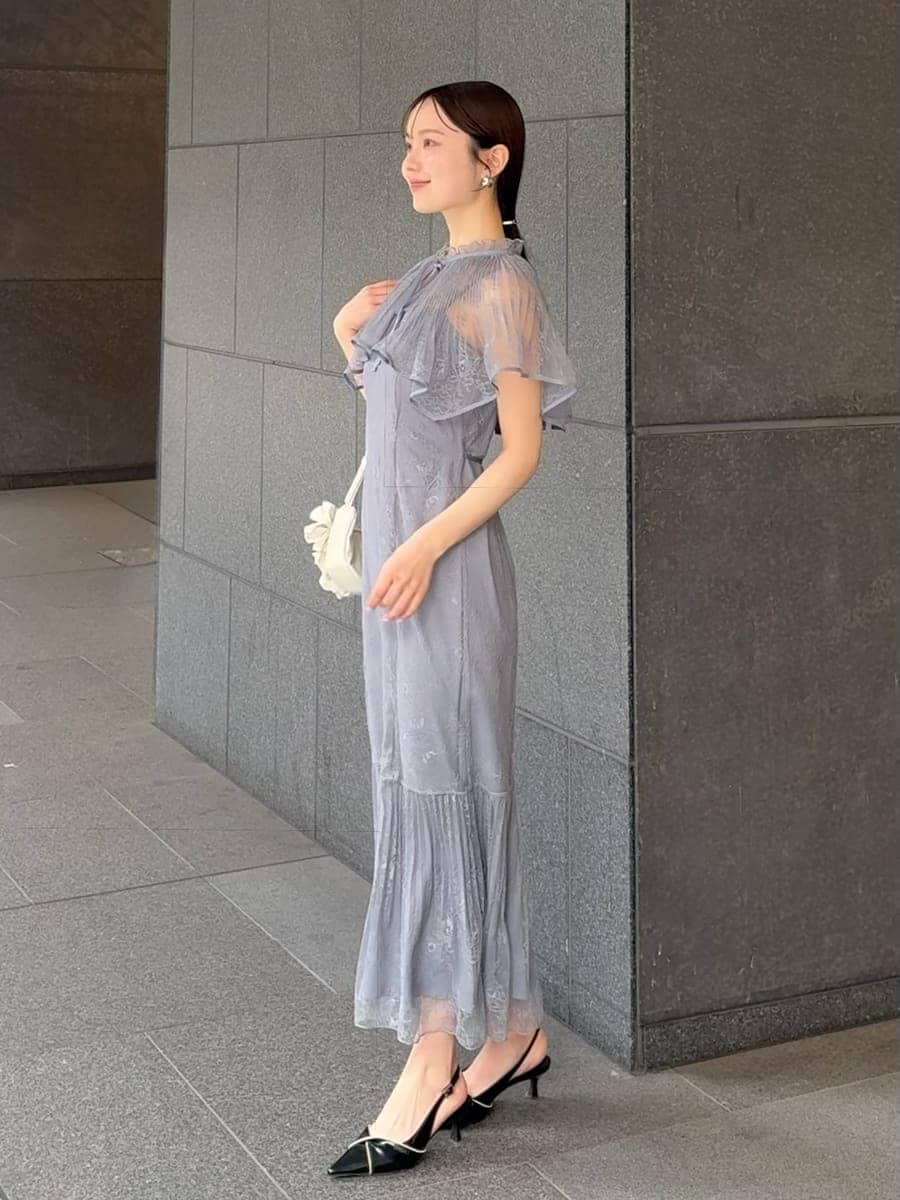 グレー系のドレス、ブラック系のパンプス、ホワイト系のハンドバッグを着用したレディースの春コーディネートの2枚目の写真