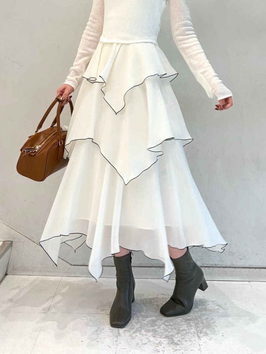 ホワイト系のワンピース、イエロー系のボストンバッグ、その他のイヤリングを着用したレディースの冬コーディネートの4枚目の写真