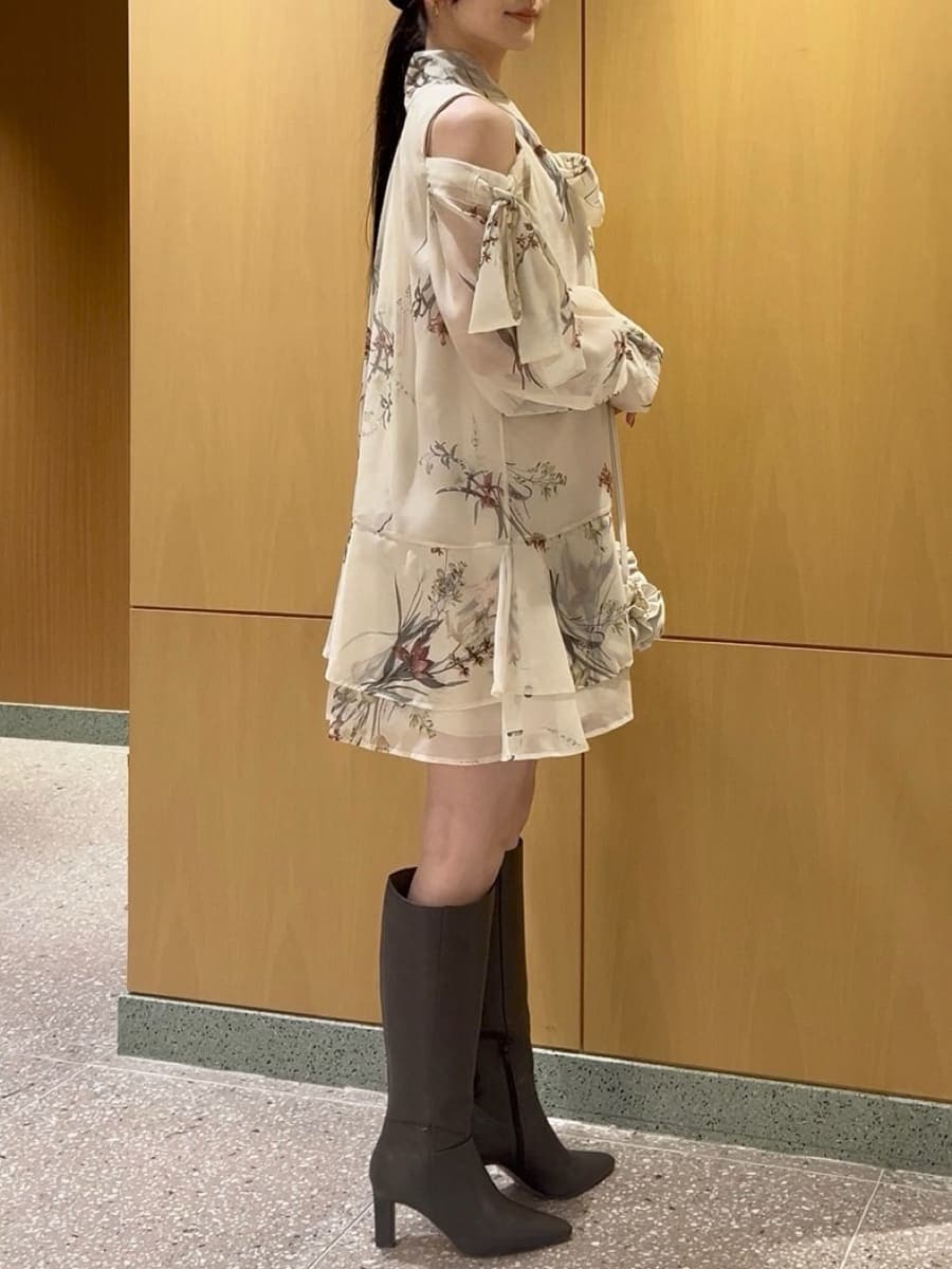 グレー系のブーツ、イエロー系のワンピース、ホワイト系のハンドバッグを着用したレディースの冬コーディネートの5枚目の写真